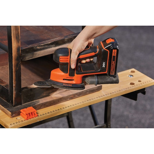 Photo de la ponceuse sans fil BLACKDECKER BD4KITCDCMSL utilisée sur un meuble en bois, tenue à la main sur une table.