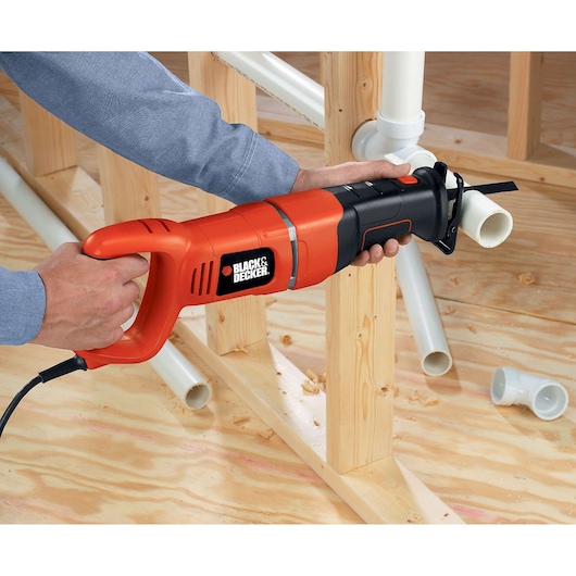 Photo de la scie sabre BLACKDECKER RS500 coupant un tuyau PVC lors d’une construction.